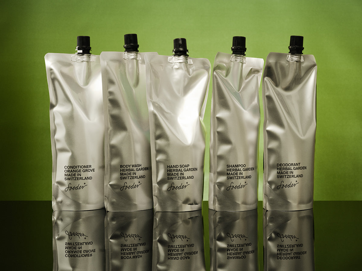 Cinq sachets de recharge argentés pour après-shampoing, Body Wash, savon pour les mains, shampoing et déodorant, sur fond vert