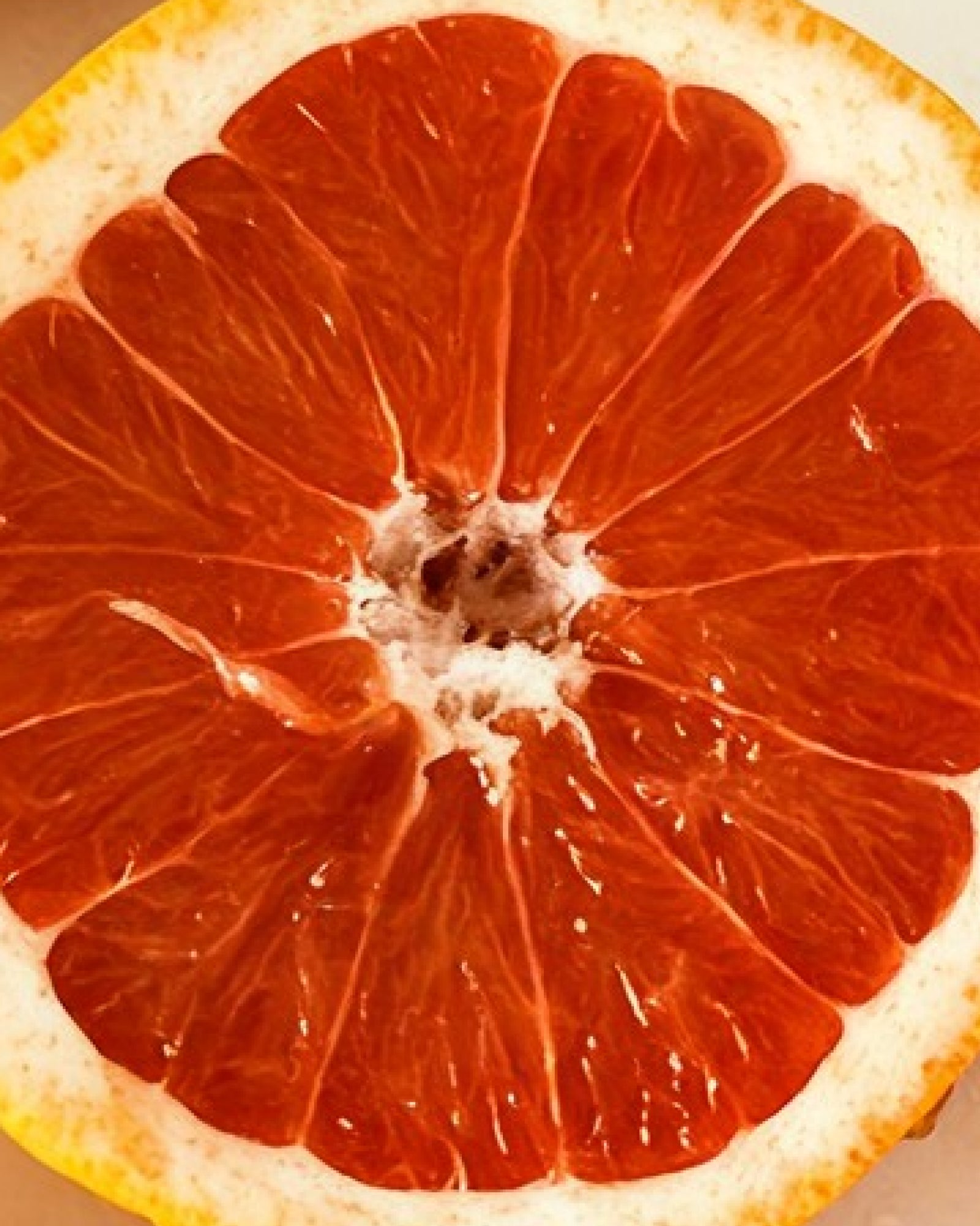 Une orange amère coupée en deux, à la chair rouge – Image d'ambiance illustrant le parfum « Season's Greetings »
