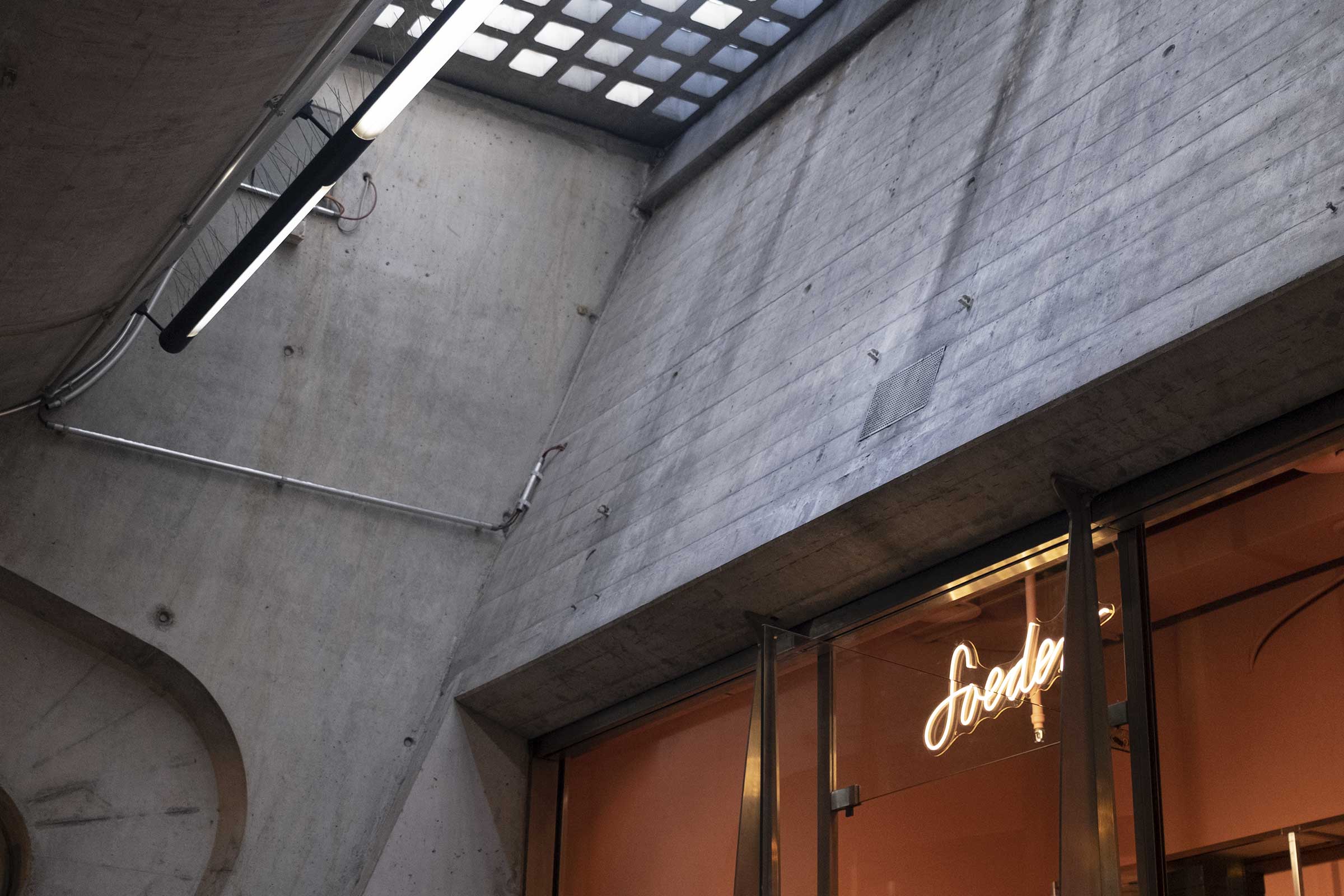 Magasin Soeder à la gare de Stadelhofen, avec une enseigne lumineuse sous un plafond en béton apparent