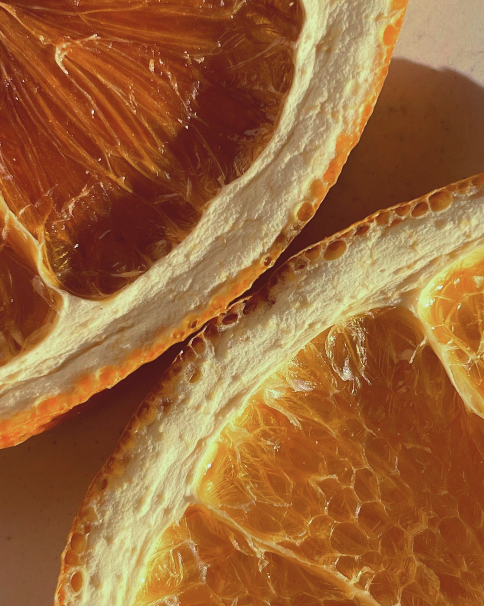 Des rondelles d'orange séchées sous une lumière chaude – image d'ambiance illustrant le parfum « Wermut Negroni »