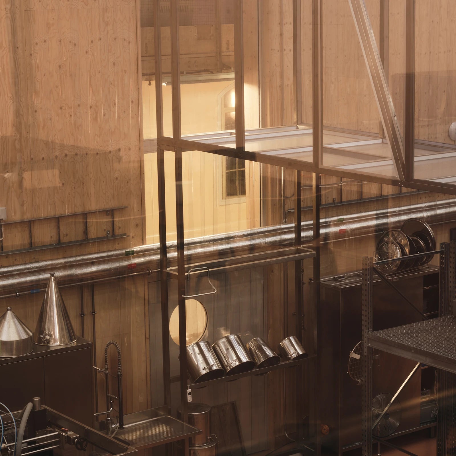 A view through the glass into the fragrance factory, with stainless steel containers and piping